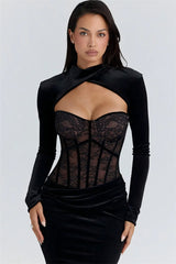 Woman wearing a black long-sleeve top with a sheer lace bodice on a light gray background