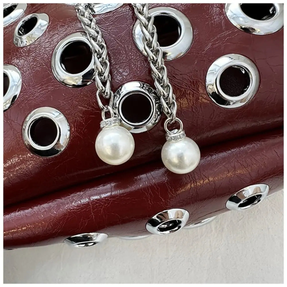 Close-up of a leather product with metal eyelets and pearl charm