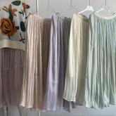 Four sheer skirts in different colors hanging on a rack against a tiled wall.