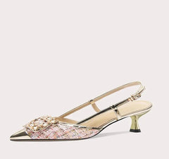 Gold high-heeled shoe with decorative element on a light gray background