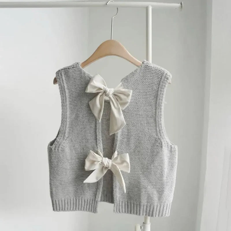 Gray knitted vest with bow details on a hanger against a white background