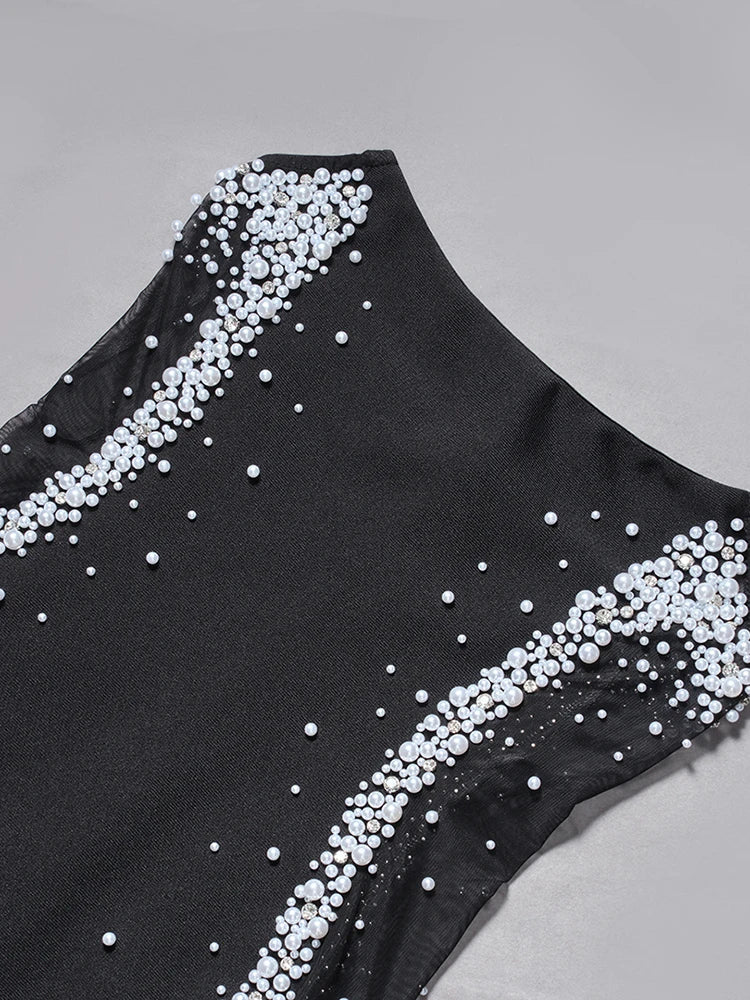 Black swimsuit with white bead embellishments on a gray background
