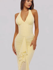 Woman wearing a yellow halter neck dress on a plain background