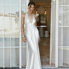 Woman in a white dress standing in a modern indoor setting with large windows.