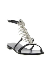 Black flat sandal with a silver rhinestone fishbone embellishment and ankle strap