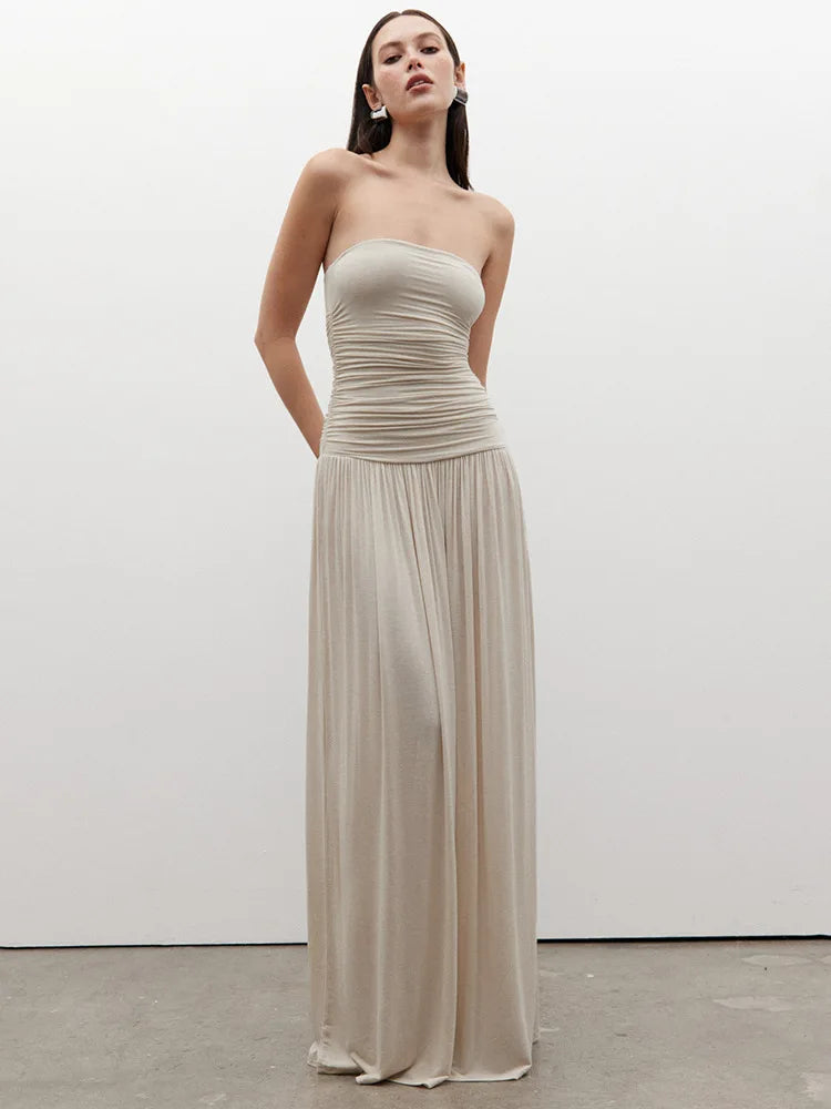 Woman wearing a strapless, floor-length beige dress against a white background