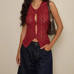 Woman wearing a red lace top and dark jeans against a beige background