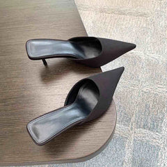 Pair of black high-heeled shoes on a wooden surface.