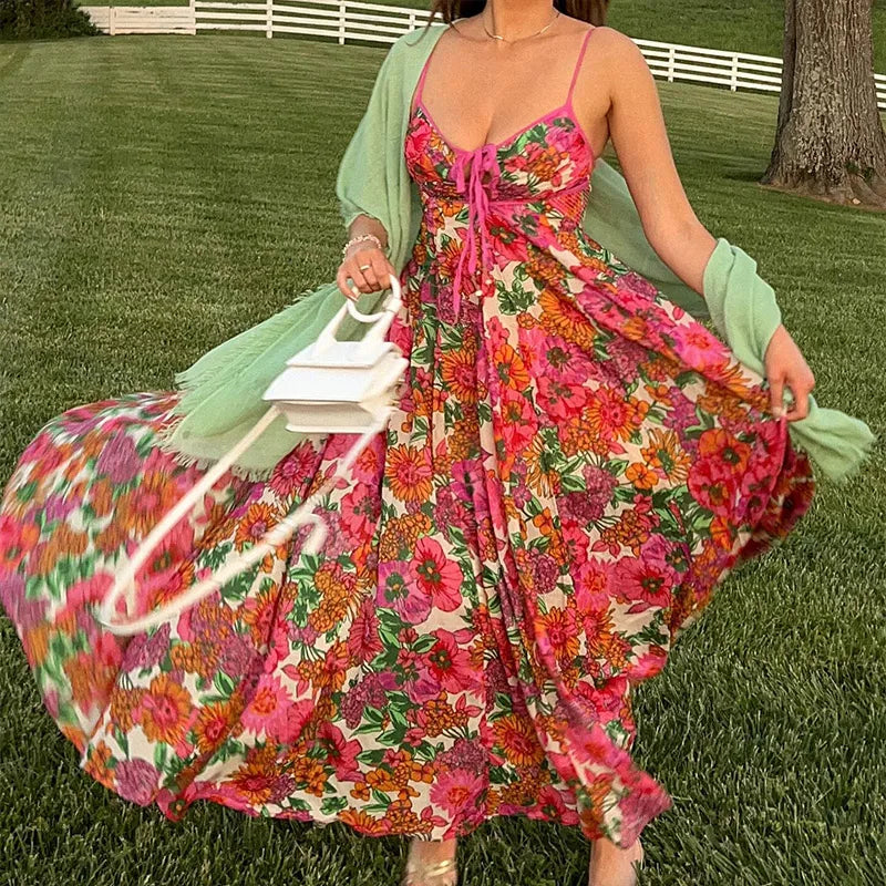Woman in a colorful floral dress holding a white bag on grass