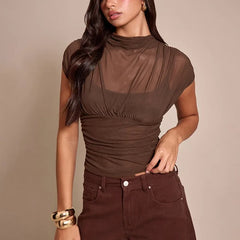 Woman wearing a brown top and pants against a beige background