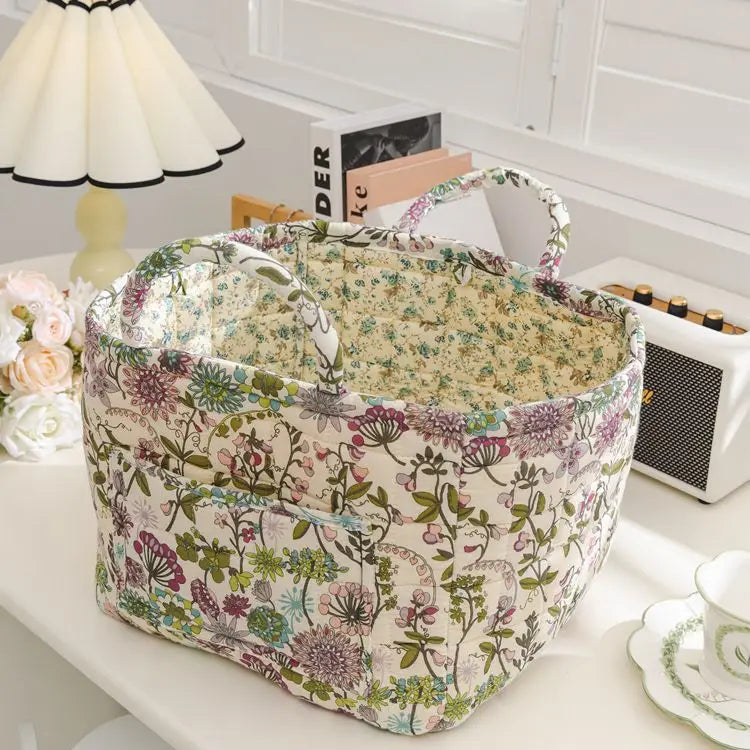 Floral-patterned fabric basket on a table with books and a lamp in the background