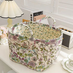 Floral-patterned fabric basket on a table with books and a lamp in the background