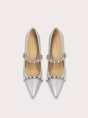 Pair of silver pointed-toe shoes with embellishments on a light gray background