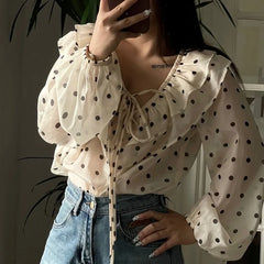 Person wearing a polka dot blouse and jeans indoors.
