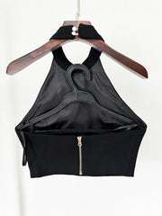 Black halter top with a zipper on a wooden hanger against a white background