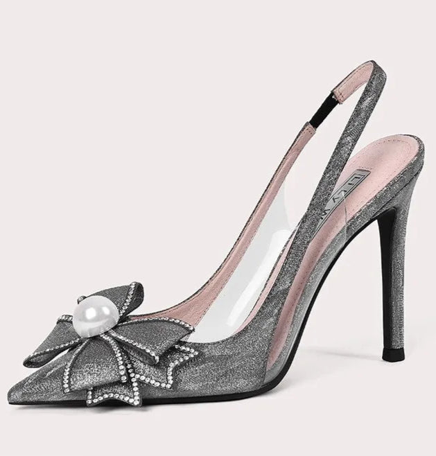 High-heeled shoe with decorative bow and pearl on a light gray background