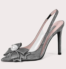 High-heeled shoe with decorative bow and pearl on a light gray background