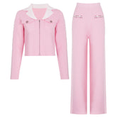 Pink knit jacket with white collar and embellished sleeves, paired with wide-leg pink trousers with white side stripes.