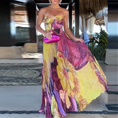 Woman in a colorful strapless dress holding a pink clutch in an indoor setting.