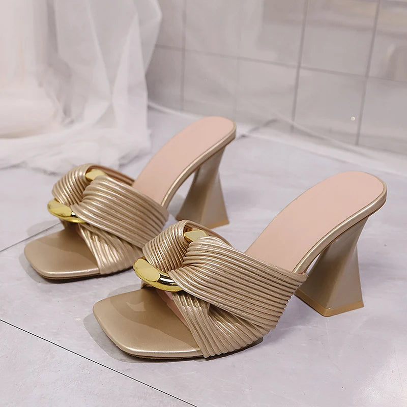 Beige high-heeled sandals with ribbed design on a light gray floor.