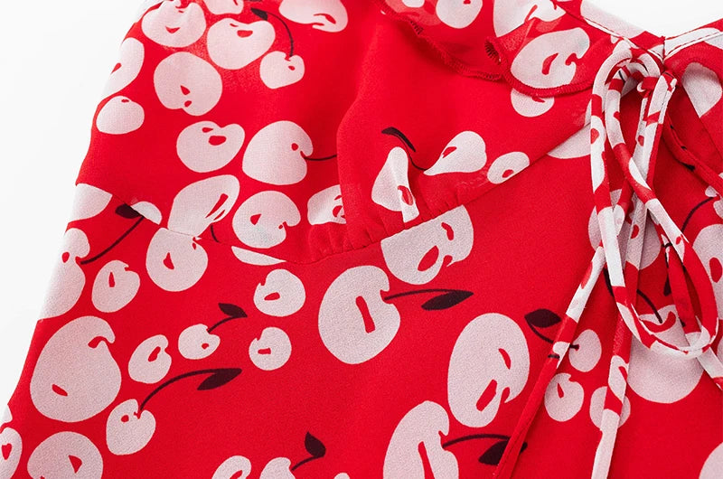 Close-up of the red cherry print fabric and ruffle strap detail on a mini dress.