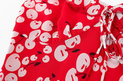 Close-up of the red cherry print fabric and ruffle strap detail on a mini dress.