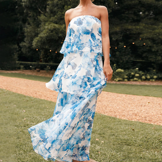 Woman wearing a strapless blue and white floral dress outdoors on a grassy area.