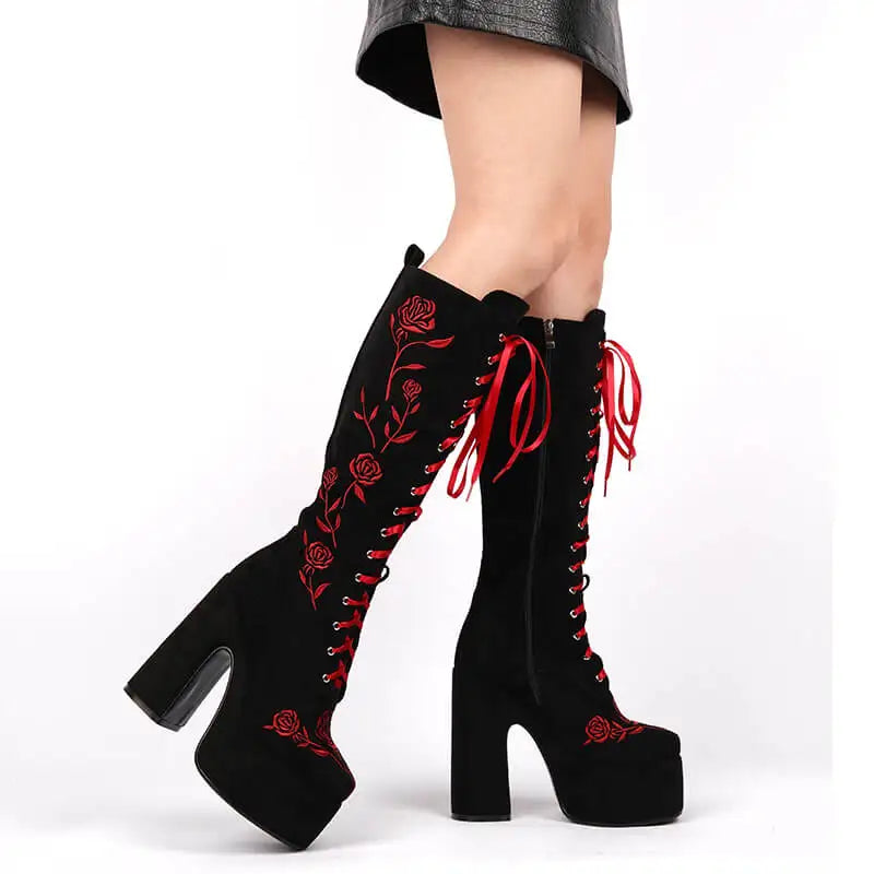Black knee-high boots with red floral embroidery on a white background