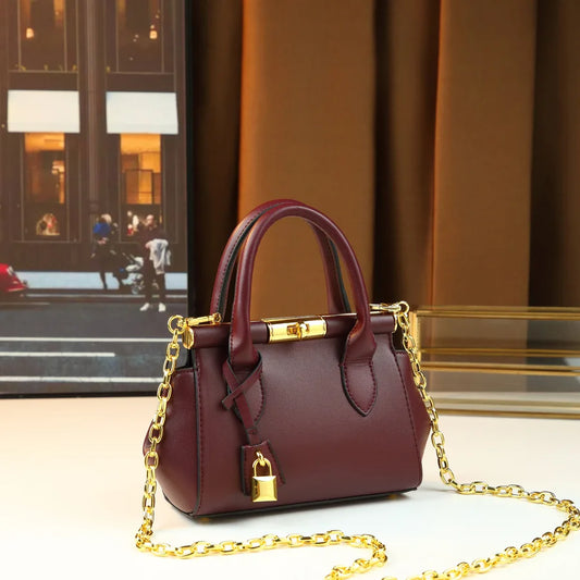Structured leather top-handle bag with gold hardware and chain strap