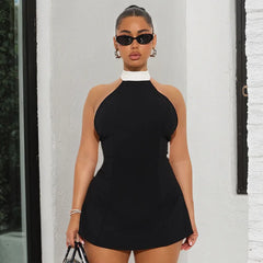 Woman wearing a black dress with a white collar against a white wall.