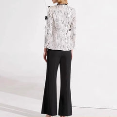 Person wearing a white lace blazer and black pants on a white background