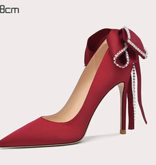 Red high-heeled shoe with decorative bow on a white background