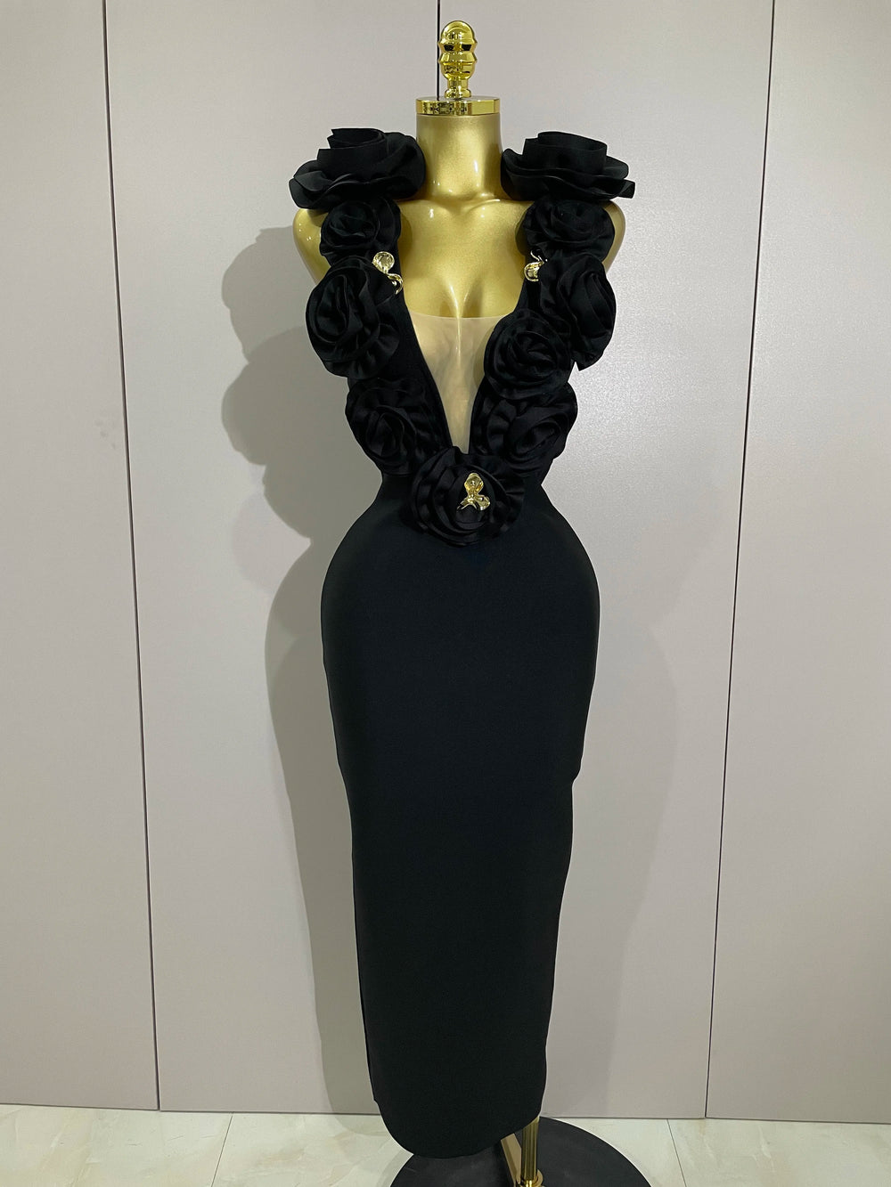 Black evening gown with floral details on a mannequin against a plain background