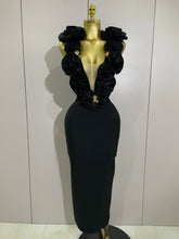 Black evening gown with floral details on a mannequin against a plain background