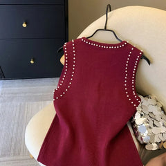 Red dress with pearl embellishments on a hanger against a neutral background