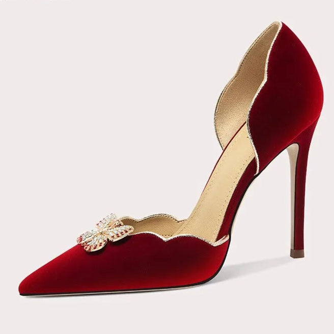 Red high-heeled shoe with decorative brooch on a white background