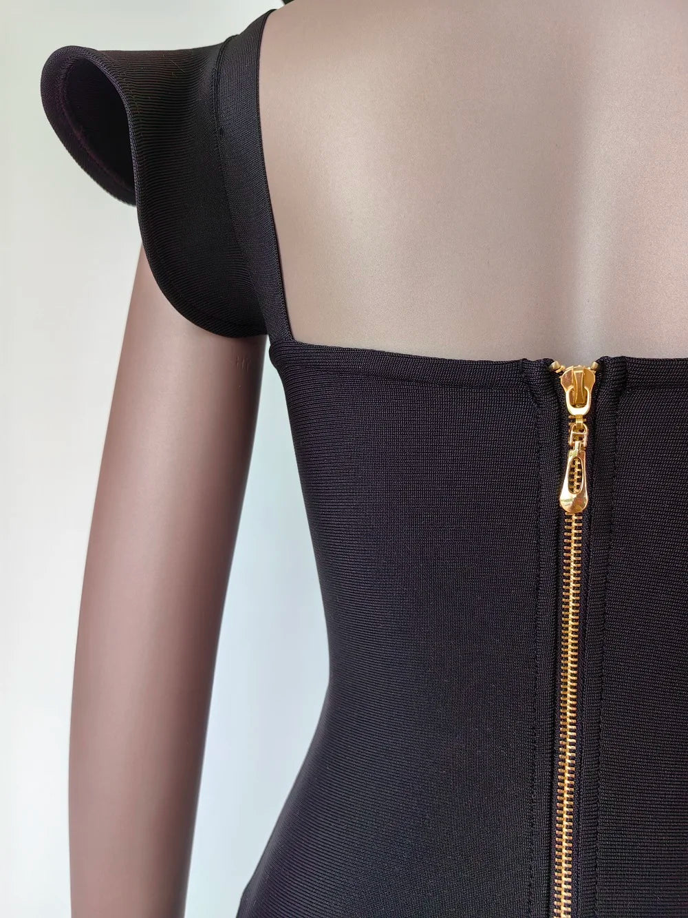Black dress with a gold zipper on a mannequin against a white background