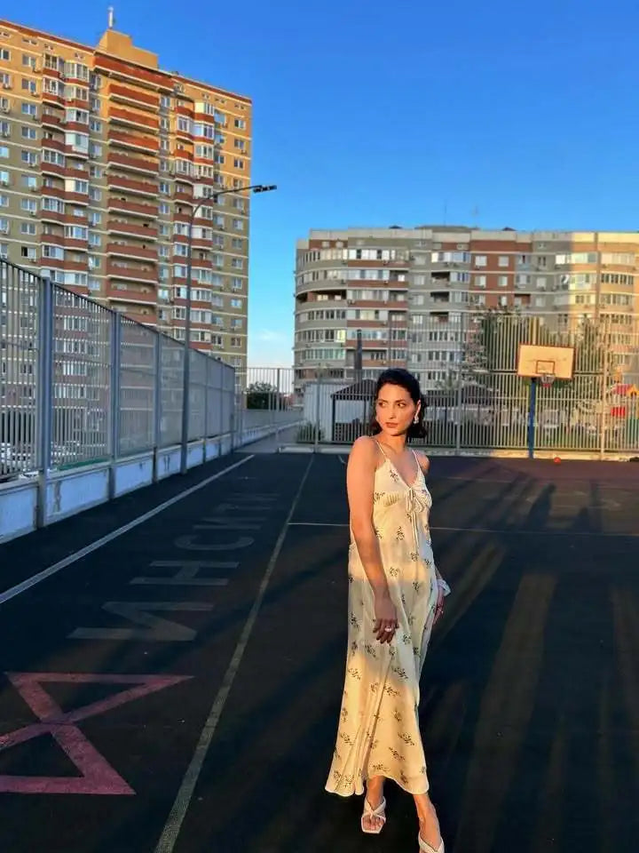 Woman in a floral dress standing on an urban rooftop with apartment buildings in the background