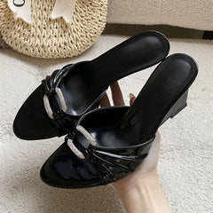 Black patent leather wedge slippers with crystal buckle and pleated detail.