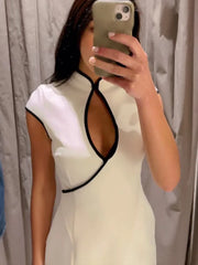 Person wearing a white dress with black accents, taking a mirror selfie.
