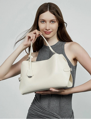 Woman holding a beige handbag against a plain background
