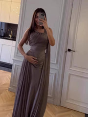 Woman in a long, flowing dress taking a mirror selfie in a kitchen.