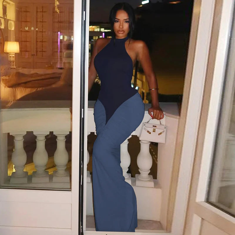 Woman in a blue jumpsuit standing on a balcony at night.