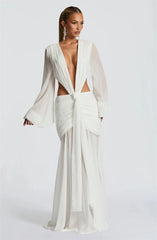 Woman wearing a white bridal gown with a plunging neckline and long sleeves on a white background