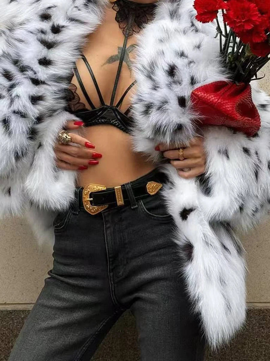 Person wearing a black and white fur coat with red flowers, black bra, and gray pants.