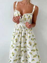 White dress with yellow lemon print held by a person against a plain background