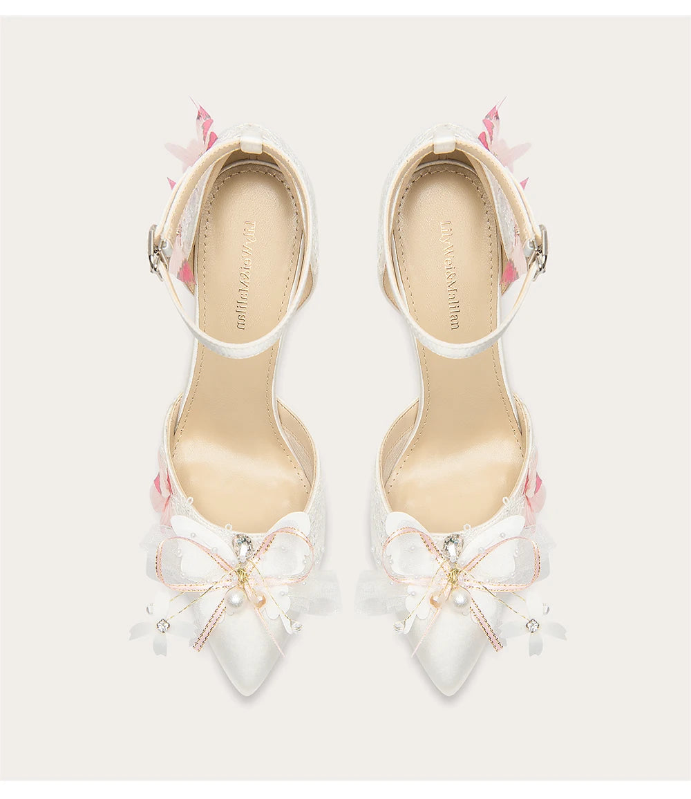 White high-heeled shoes with floral decorations on a light gray background