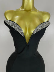 Black evening gown with crystal embellishments on a mannequin against a gray background