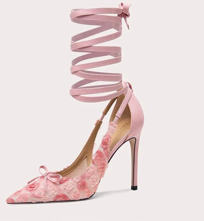 Pink high-heeled shoe with floral design and ribbon on a white background