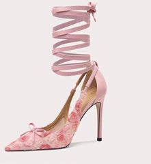 Pink high-heeled shoe with floral design and ribbon on a white background